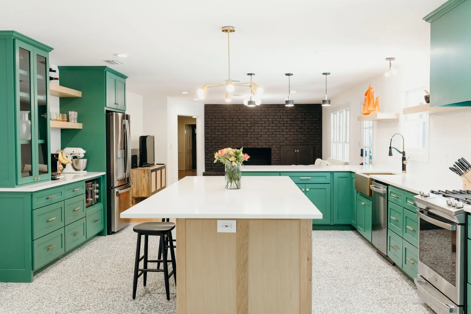 Open kitchen with green cabinets and oak island